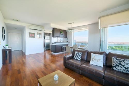 a living room with a brown couch and a kitchen at Puerto Madero Piso 20 Vista al Rio frente a Hilton in Buenos Aires