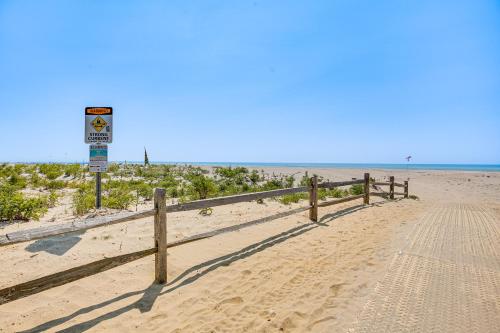 a sandy beach with a fence and a sign on it at Family-Friendly Ocean City Condo Walk to Beach! in Ocean City