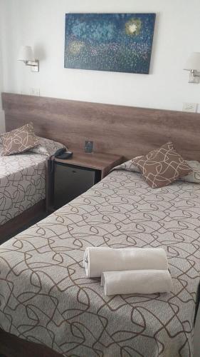 a bedroom with two beds and a painting on the wall at HOTEL ROMA DE TANDIL in Tandil