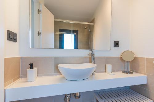 uma casa de banho com um lavatório branco e um espelho. em Pareado con piscina en el Rompido em El Rompido