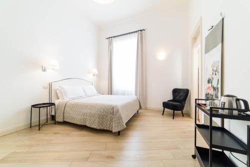 ein weißes Schlafzimmer mit einem Bett und einem Stuhl in der Unterkunft One&One in Salerno