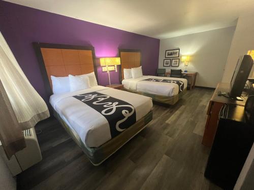 two beds in a hotel room with purple walls at La Quinta Inn by Wyndham Amarillo Mid-City in Amarillo