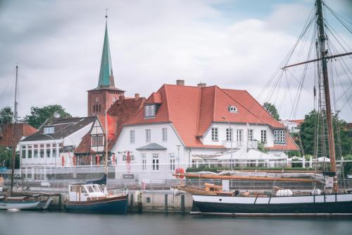 a group of boats docked in a harbor with a church at KRABBES neue Hafenliebe in Neustadt in Holstein