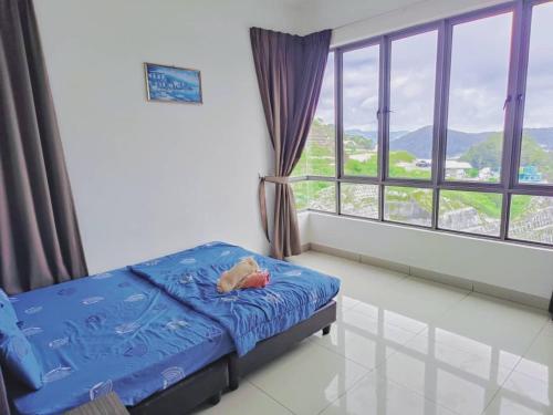 キャメロンハイランドにあるCooling Point Homestay @ Palas Horizon Residenceのベッドと大きな窓のある寝室