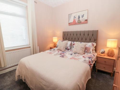 a bedroom with a bed and two lamps and a window at Myrtle Cottage in Morpeth