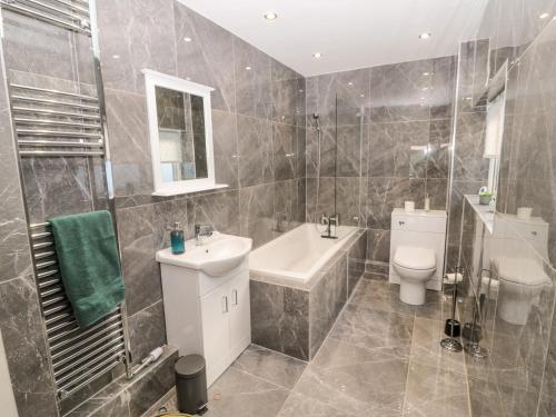 a bathroom with a sink and a toilet and a tub at Myrtle Cottage in Morpeth