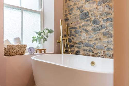 a bath tub in a bathroom with a stone wall at 3 Beck Head Kirkby Lonsdale in Kirkby Lonsdale