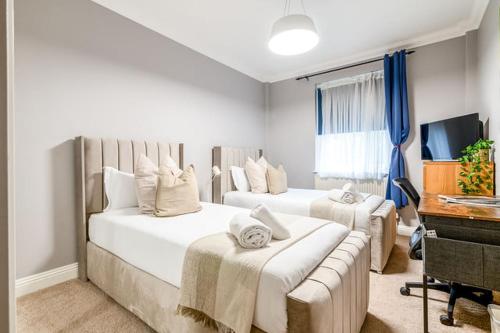 a bedroom with two beds and a desk and a television at LiveStay 2BR/2BA with Communal Pool, Sauna & Gym in London
