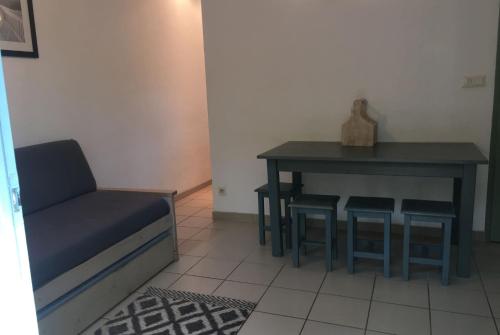 una mesa y un taburete en una habitación con una mesa y una silla en maisonnette 6 pers dans résidence avec piscine, en Arès