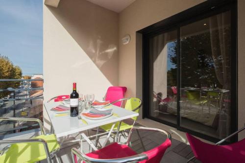 a table and chairs on a balcony with a bottle of wine at T2 haut de gamme avec vue Bassin in Andernos-les-Bains