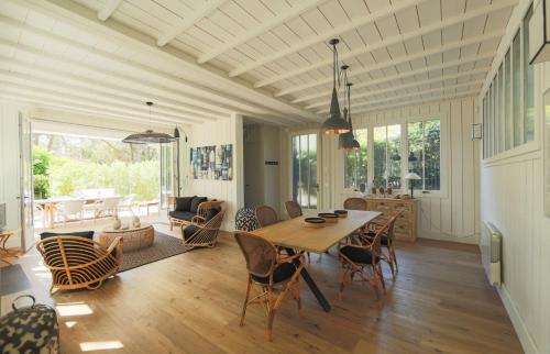 a dining room and living room with a table and chairs at CABANE JASMIN au CAP FERRET in Cap-Ferret