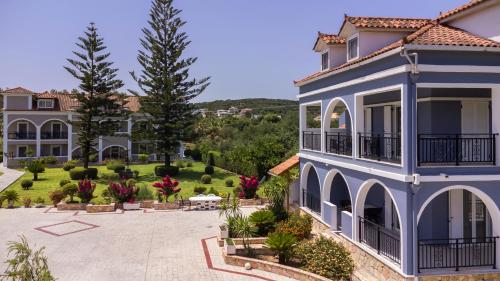 a large blue house with a courtyard and trees at Sofia - Yiota Studios & Apartments in Tsilivi