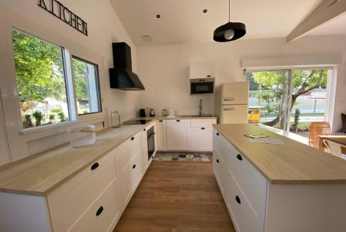 uma grande cozinha com armários brancos e uma grande ilha em VILLA DES BECASSES - Andernos les Bains em Andernos-les-Bains