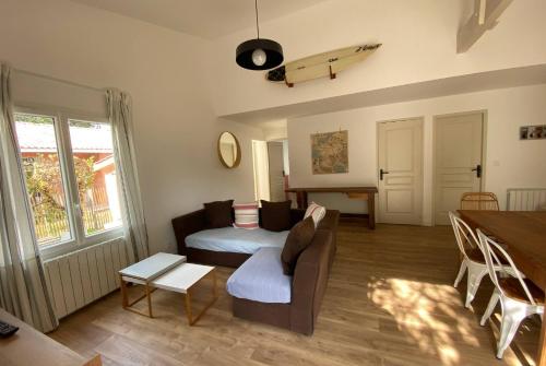 uma sala de estar com um sofá e uma prancha de surf na parede em VILLA DES BECASSES - Andernos les Bains em Andernos-les-Bains
