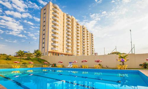 a hotel with a swimming pool in front of a tall building at FLAT Golden Dolphin Express in Caldas Novas