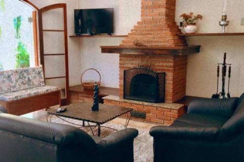 uma sala de estar com um sofá e uma lareira em Chácara Morada do Sol - (pé na represa) em Igaratá