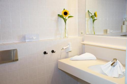 a bathroom with a sink and a vase with a sunflower at Atemberaubende Aussicht, direkter Pistenzugang in Deutschberg