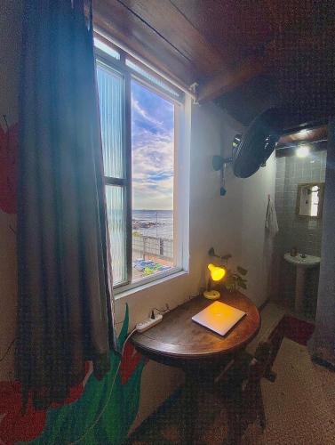a room with a table and a window with a view of the ocean at CasAMARelo Hostel in Salvador