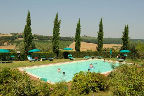 a swimming pool with people in it with trees and umbrellas at Agriturismo I Fuochi in Valiano