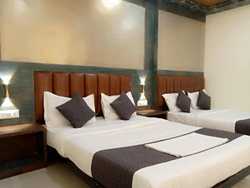 two beds in a hotel room with two lamps at TRI HOTEL in Mumbai