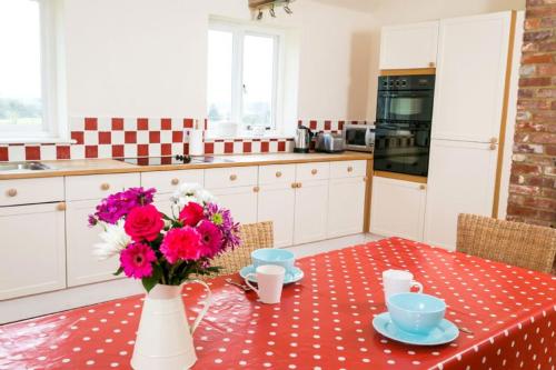 a kitchen with a table with a vase of flowers at Coach House Barn in Cranleigh