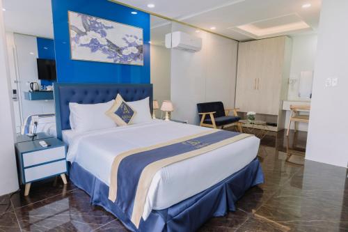 a bedroom with a large bed with a blue wall at Arina Luxury Hotel - Vincom Tay Ninh in Tây Ninh