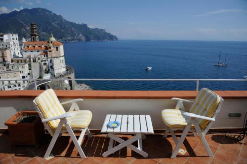 two chairs and a table on a balcony overlooking the water at Casa Rossa in Atrani