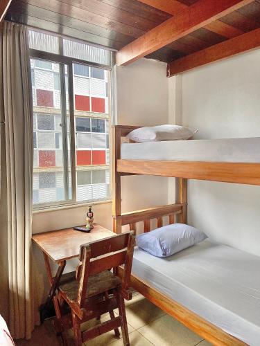 a room with two bunk beds and a desk and a window at CasAMARelo Hostel in Salvador