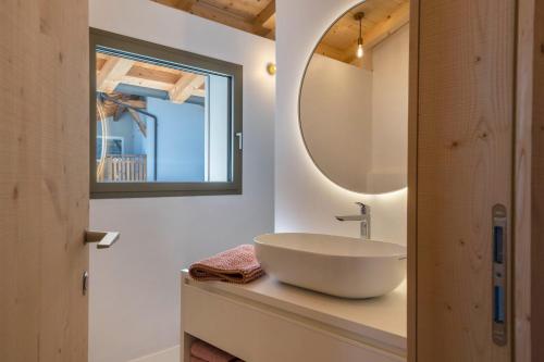 een badkamer met een wastafel en een spiegel op een aanrecht bij Lena Dolomites Luxury Suite in Villnoss