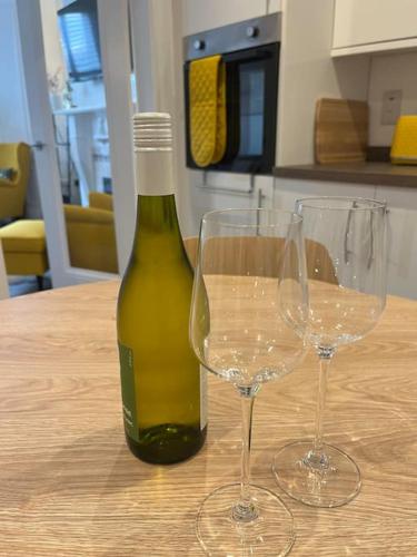a bottle of wine and two wine glasses on a table at Charming Victorian Terrace, South Belfast in Belfast