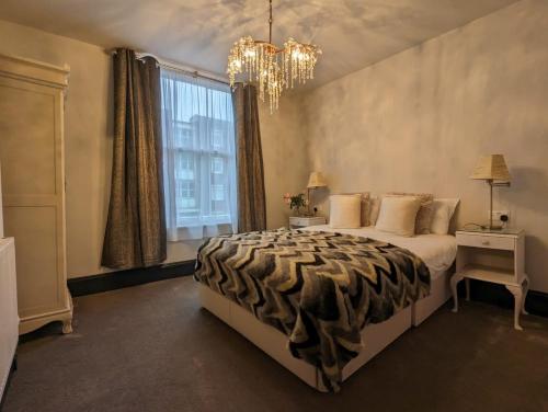 - une chambre avec un lit, un lustre et une fenêtre dans l'établissement Salt Life Belgravia Apartment, à Brighton et Hove