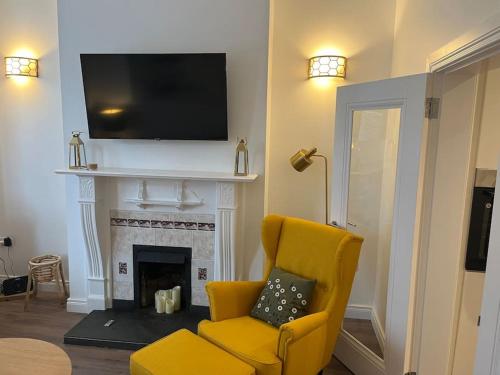 a living room with a yellow chair and a fireplace at Charming Victorian Terrace, South Belfast in Belfast