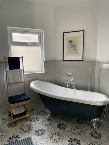 a bath tub in a bathroom with a chair at Charming Victorian Terrace, South Belfast in Belfast