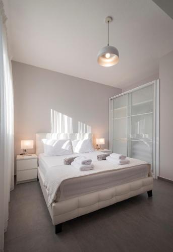 a white bedroom with a large bed with white pillows at Bellevue Villas with private pool in Hanioti