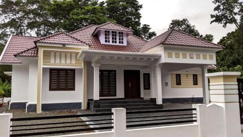 Casa blanca con techo rojo en Royal Home, en Kuravalangād