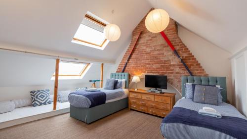 a attic bedroom with two beds and a tv at Thalassa in Walberswick