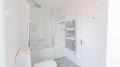 a white bathroom with a shower and a toilet at Thalassa in Walberswick