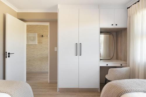 a bedroom with two beds and a white cabinet at Coral Island 204 in Bloubergstrand