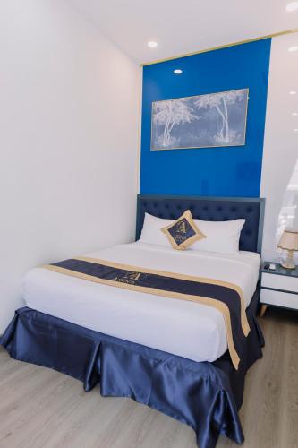 a bedroom with a large bed with a blue wall at Arina Luxury Hotel - Vincom Tay Ninh in Tây Ninh