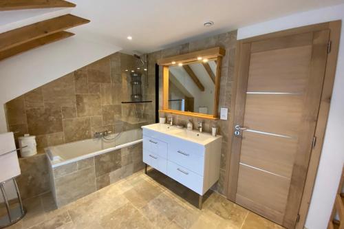 ein Badezimmer mit einem Waschbecken, einer Badewanne und einem Spiegel in der Unterkunft Gîte dans les Vosges Gite du Feing des Loges in Vagney