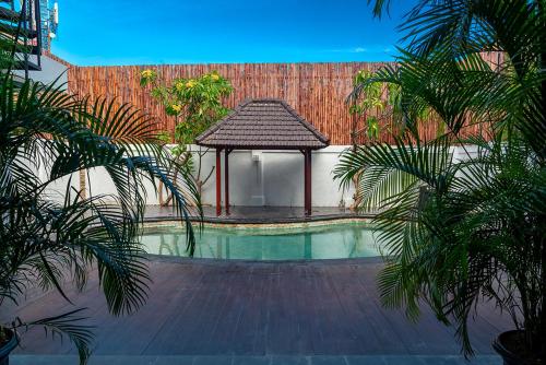 Private Urban Villa Denpasar في دينباسار: مسبح مع شرفة والنخيل