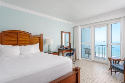 a bedroom with a bed and a balcony with the ocean at The Pensacola Beach Resort in Pensacola Beach