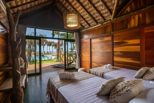 a bedroom with two beds and a large window at Rancho Noé Cumbuco in Caucaia
