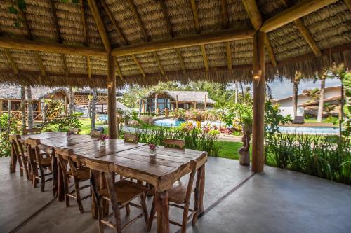 a long wooden table and chairs in a room with a pool at Rancho Noé Cumbuco in Cumbuco