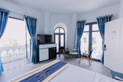 a bedroom with blue curtains and a bed with a tv at Arina Luxury Hotel - Vincom Tay Ninh in Tây Ninh