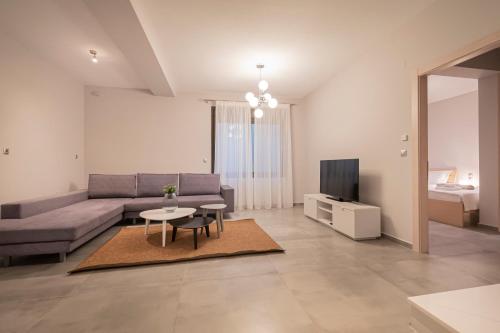 a living room with a couch and a table and a tv at Bellevue Villas with private pool in Hanioti