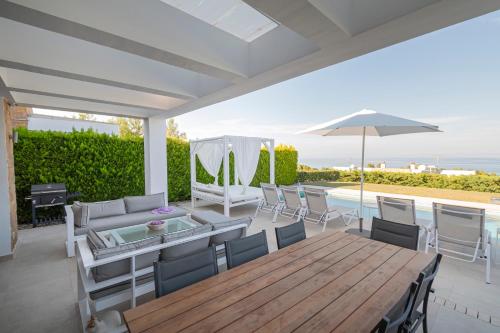 a patio with a table and chairs and an umbrella at Bellevue Villas with private pool in Hanioti