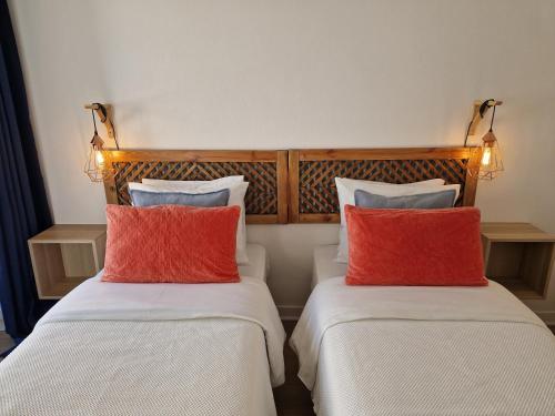 two beds with red and white pillows in a room at Bea's Bed & Breakfast in Tavira