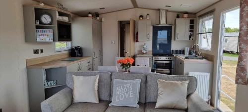 a caravan kitchen and living room with a couch and a table at Littlesea-wv55 Weymouth in Wyke Regis