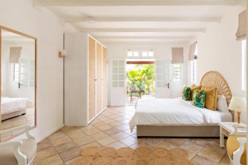 a white bedroom with a bed and a mirror at Quaint 4BDR villa with pool in Grand Gaube in Grand Gaube